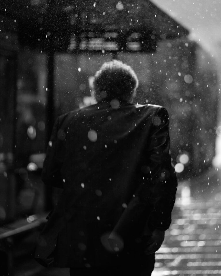 Black & white street photography by Joshua K. Jackson. Man walking in rain.