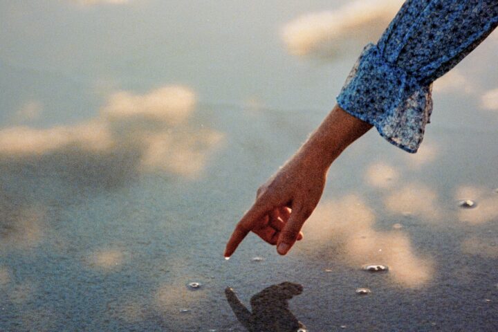 Color film photography by Jakob Lilja-Ruiz. Hand in water, reflections of the sky