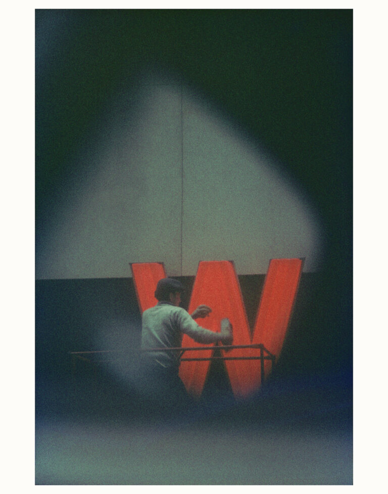 Street photography NYC. A man painting a red W sign by Saul Leiter