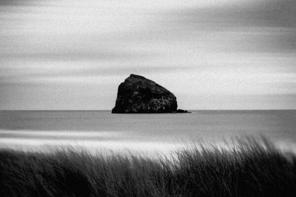 Black & white landscape photo by Adrian Vila. Black rocky island in the sea.