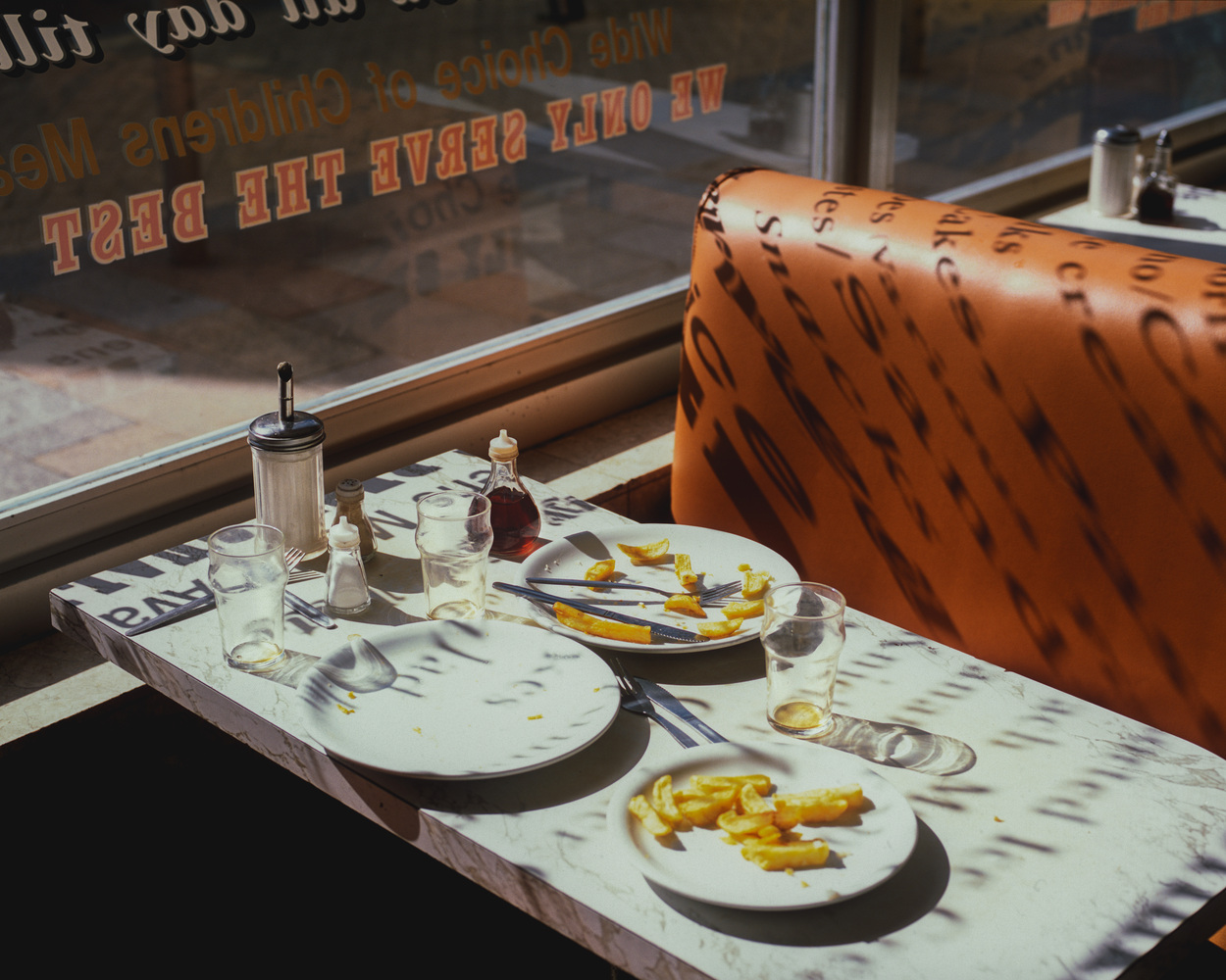 Color photography by Ian Howorth of a table with empty plates in a fish and chip shop.