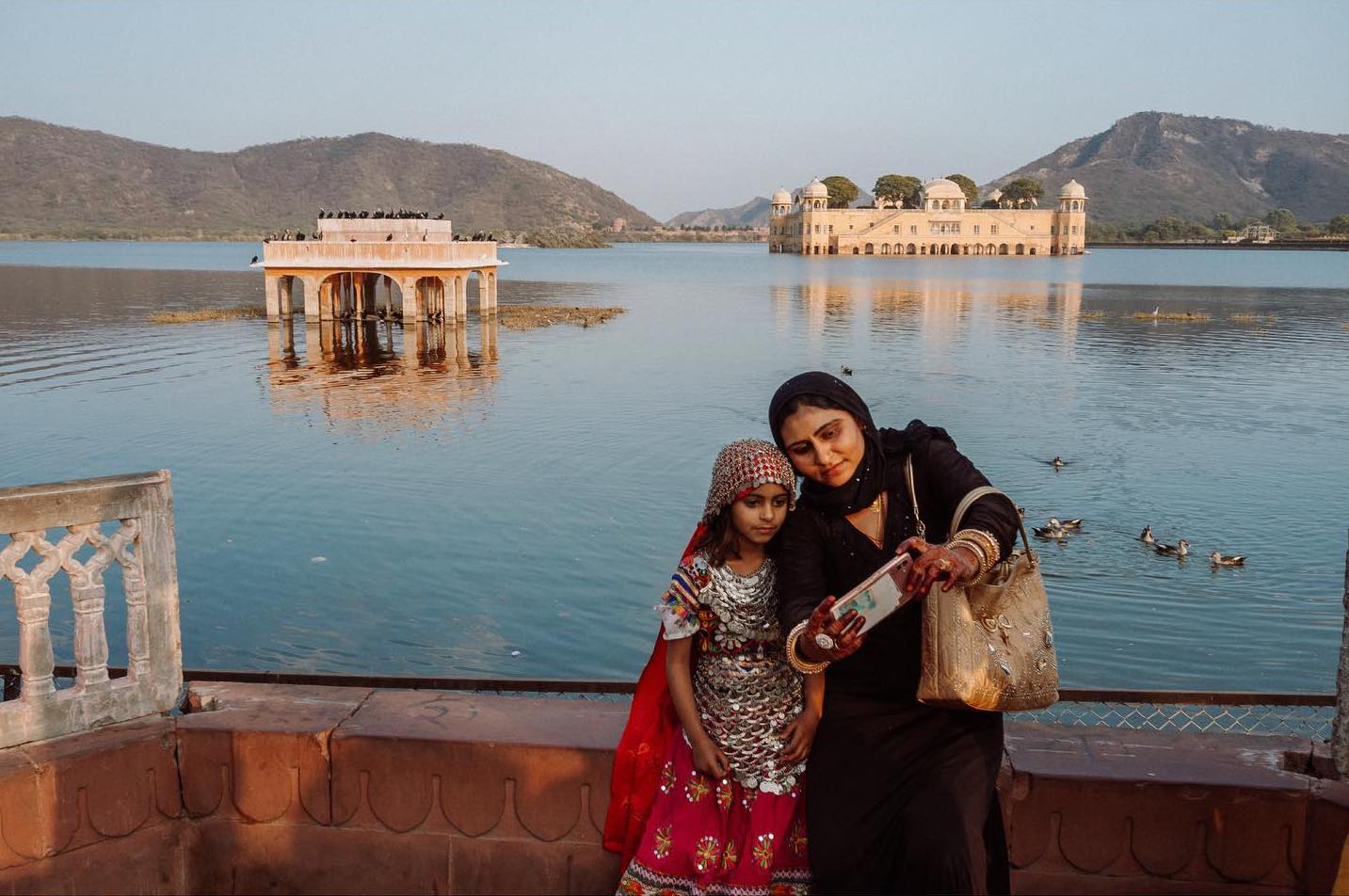 Photo of a mother and daughter taking a selfie in front of a lake by Jody Macdonald