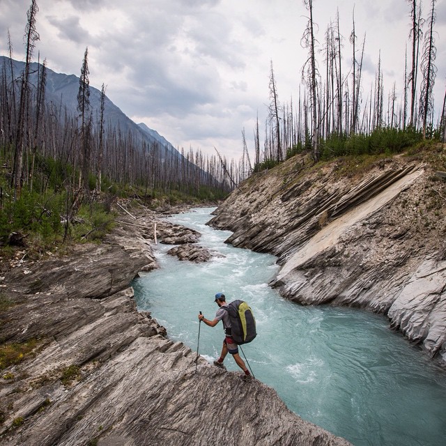 Travel photography by Jody Macdonald. A man walking alongside a river with mountains in the background by Jody Macdonald