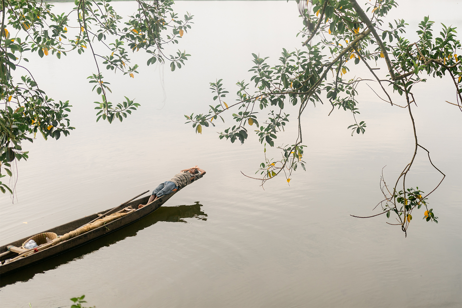 Color travel photography of a fisherman on boat in Guwahati, India by Lonav Bharali