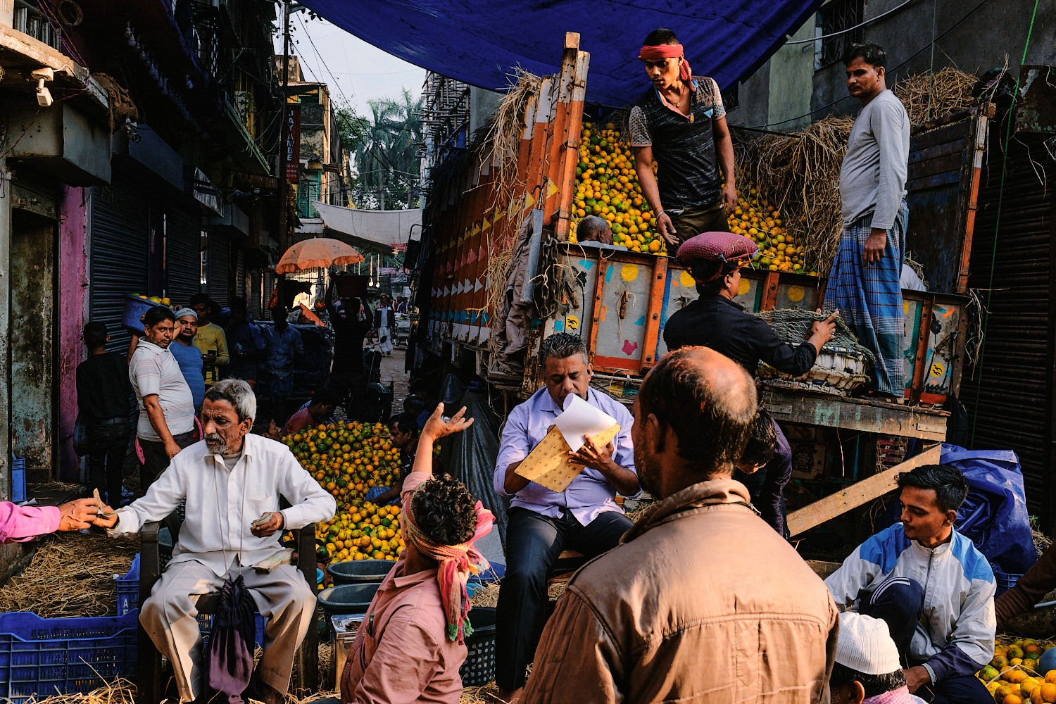 Street photography by Eduardo Ortiz. Men unloading a truck full of flowers in Kolkata, India