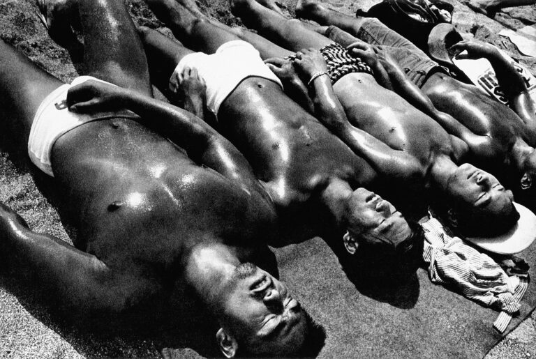 Black & white photo of a group of men sunbathing by Daido Moriyama