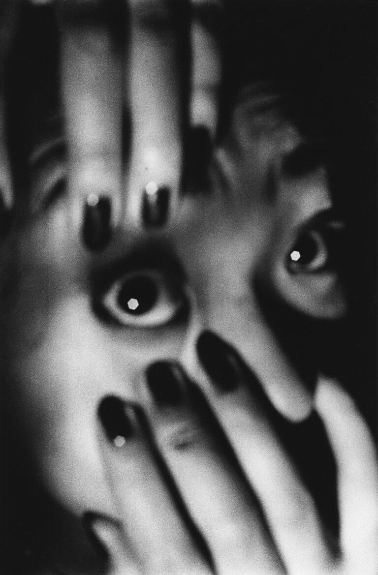 Black & white photo of a woman holding her eye open by Daido Moriyama