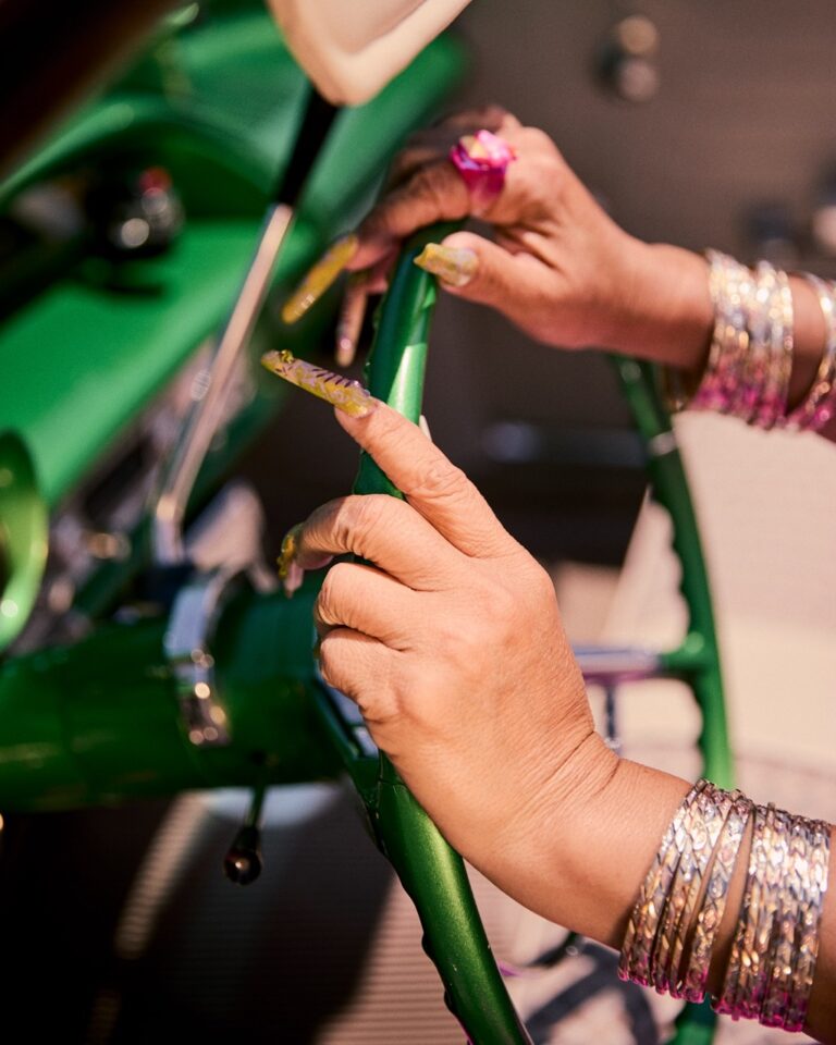 Documentary photo by Owen Harvey. Woman's hands on a green steering wheel.