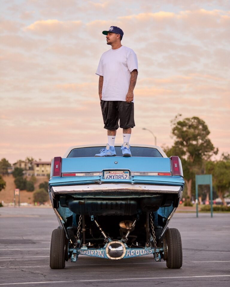 Documentary photography by Owen Harvey. Man stood on the back of a car. From the project Ground Clearance LA