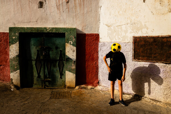 color street photo of boy playing soccer in Morocco by Nicola Fioravanti