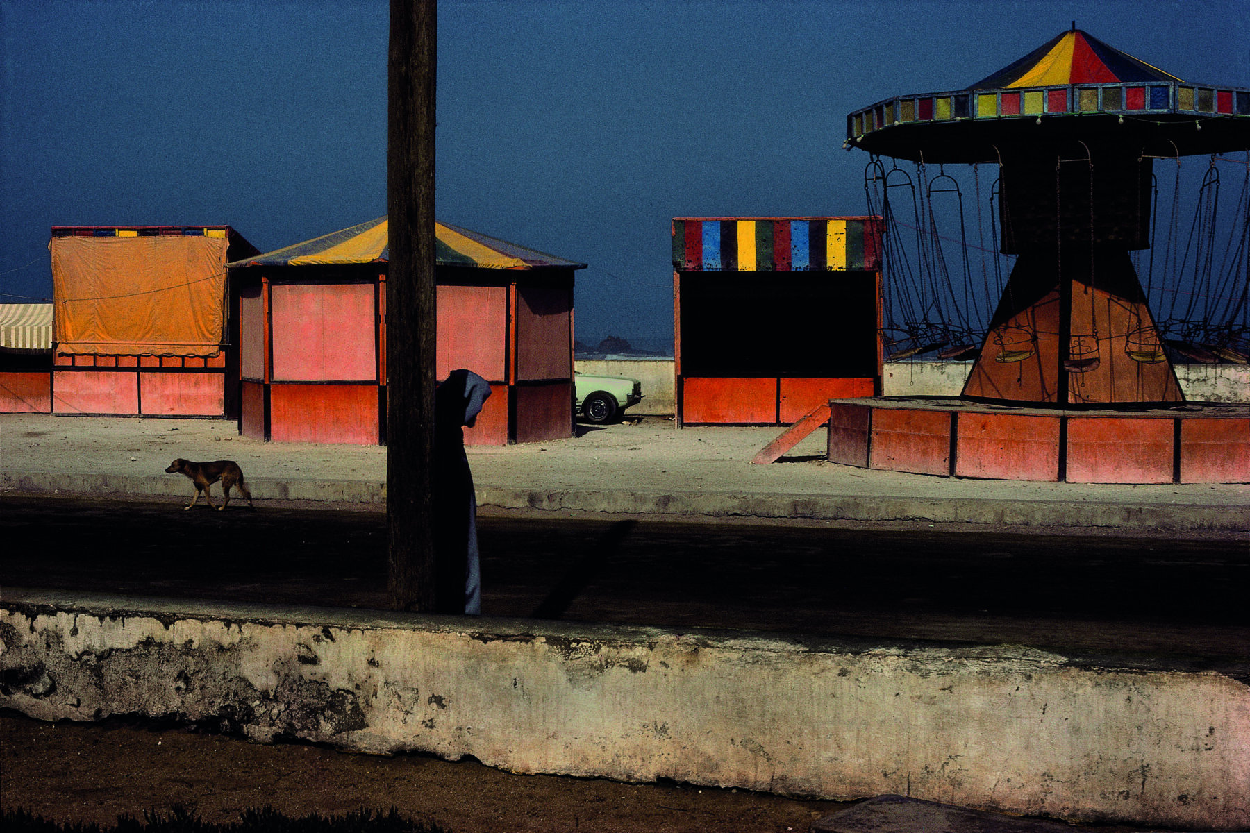 Colourful amusement stands near the beachfront in Essaouira, Morocco by Harry Gruyaert