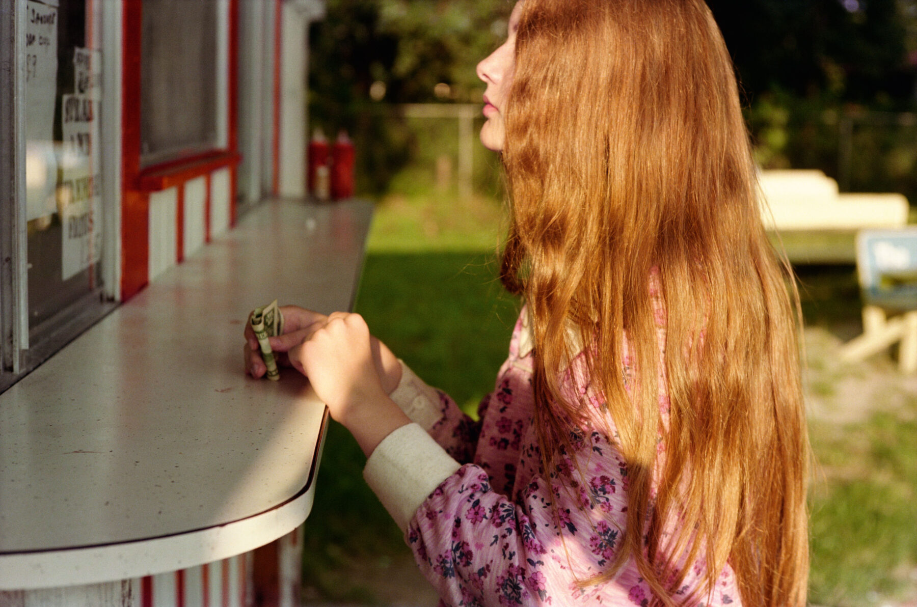 Color photography by William Eggleston. A redheaded girl at a roadside drinks stand