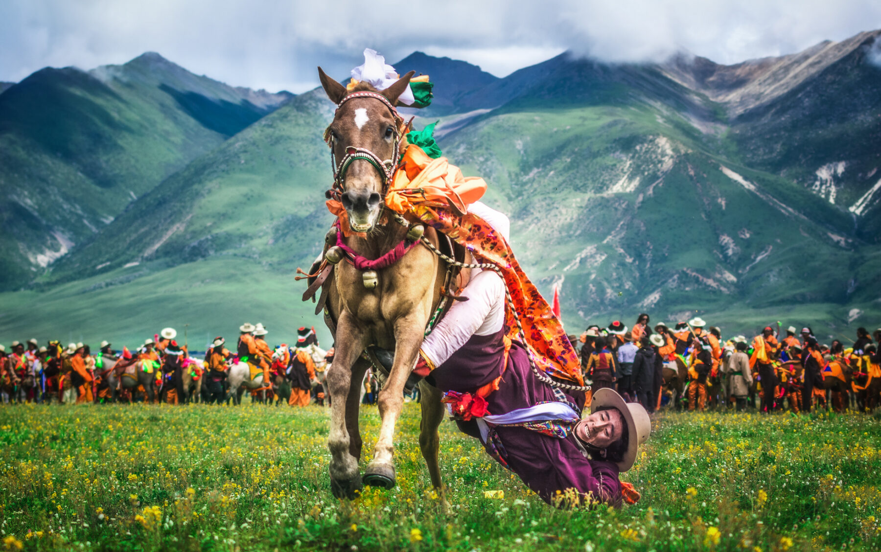 Color photo of an acrobatic horse rider with mountains in the backdrop in Tibet