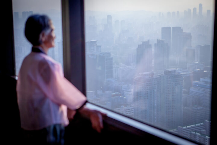 Photo by Björn Steinz of a woman in traditional Korean clothes looking over the Seoul skyline