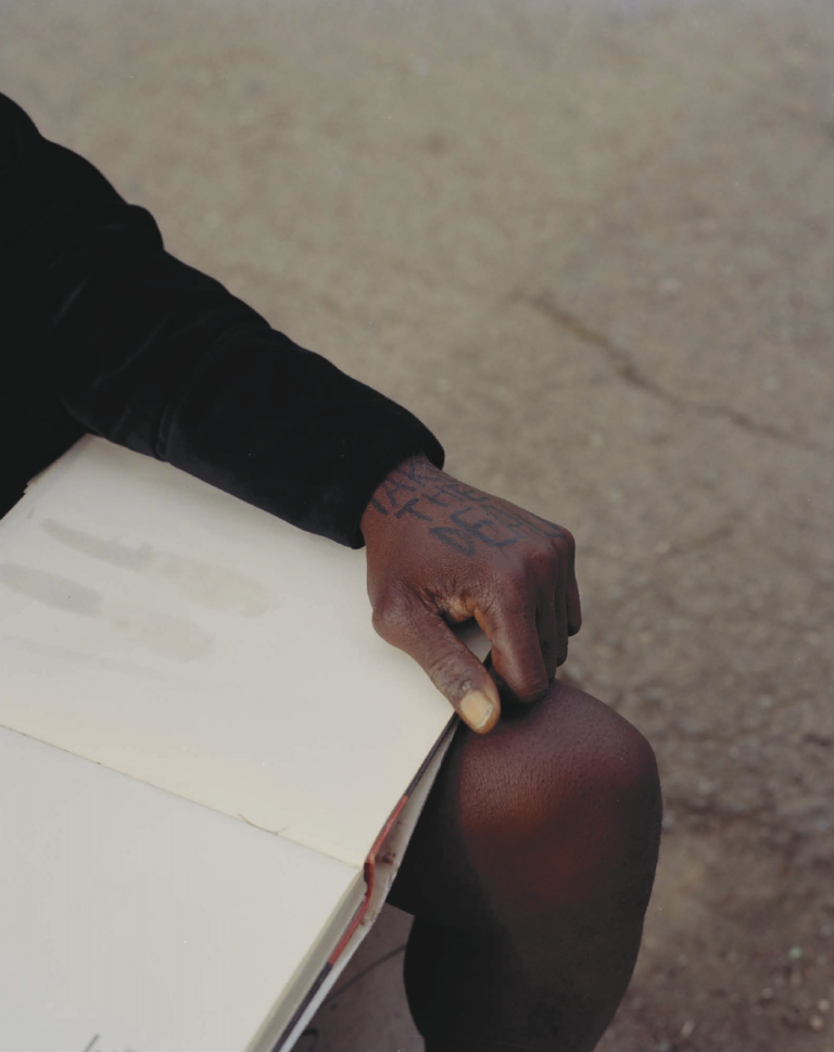 Color documentary photography by Mikel Bastida. From the book "Anarene". Tattooed hand on book.