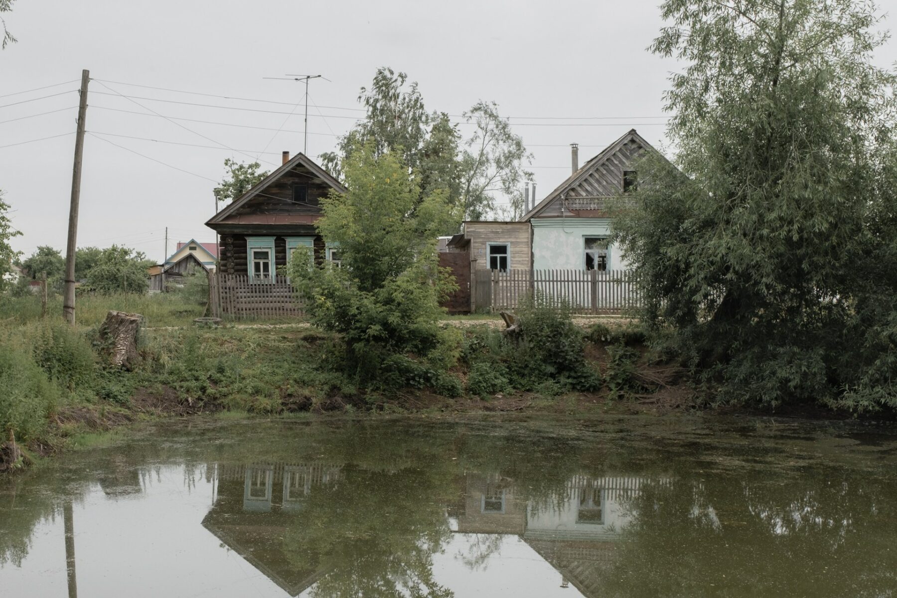 "Kilelle. Towards Home" by Ksenia Maksimova. Landscape photography of wooden houses next to a river