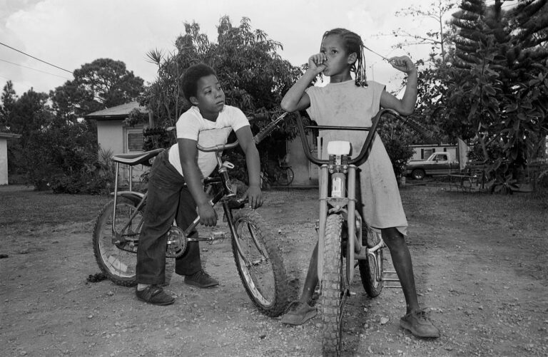 Black & white photo of two children with bicycles by Sage Sohier.