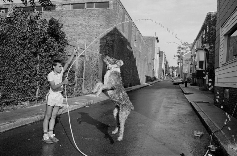 B&W photo by Sage Sohier. Boy playing with dog.